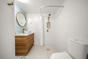 a white bathroom with a sink and a mirror at Coastal Drift - Beach Access Pool Spa Gym in Marcoola