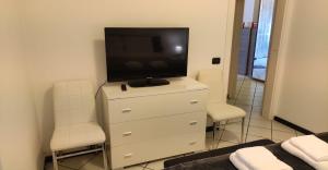 a bedroom with a tv on a dresser with two chairs at casa raffa megaride's dépendance in Como
