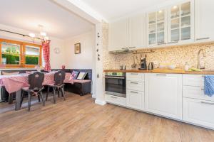 a kitchen with white cabinets and a table with chairs at Alpen Lodge Chiemgau in Schleching