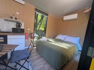 a bedroom with a bed and a table and a window at The Secret Place by Tiny Away in Palmvale