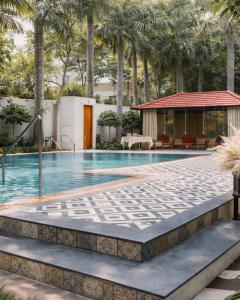 a swimming pool with palm trees and a building at Amantran Farm Retreat in Varanasi