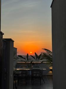 a table and chairs on a balcony with the sunset at VELORA - Sodic Penthouse with jacuzzi & big terrace over New Cairo view in New cairo +28 photos