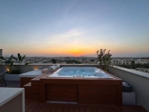 a hot tub on a balcony with a sunset at VELORA - Sodic Penthouse with jacuzzi & big terrace over New Cairo view in New cairo