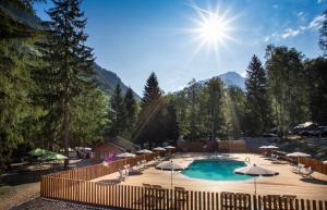 a swimming pool with umbrellas and a sunvisor at Huttopia Bozel en Vanoise in Bozel