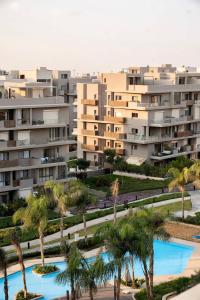 an apartment complex with palm trees and a swimming pool at VELORA Serviced Rooftop Studio With Private Jacuzzi in Sodic New cairo in New cairo