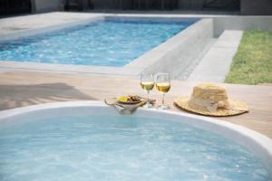 a pool with two glasses of wine and a hat and a plate of food at Gracieux Villa Lusso in Miyakojima