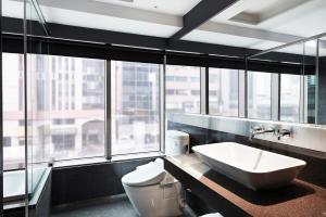a bathroom with a sink and a toilet and windows at CHECK inn Taipei Nanjing in Taipei