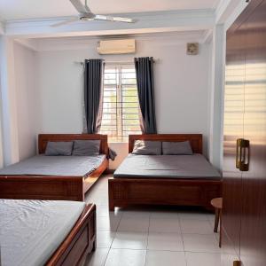 two beds in a room with a window at Nhà Nghỉ Bình An in Kỳ Lừa