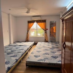 two beds in a room with a window at Nhà Nghỉ Bình An in Kỳ Lừa