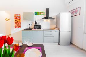 a kitchen with a refrigerator and a table with red flowers at 7th Floor - Donoratico in Cagliari