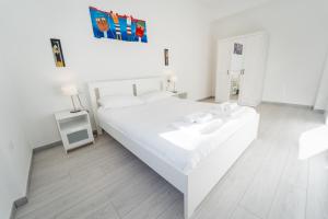 a white bedroom with a white bed and a sink at 7th Floor - Donoratico in Cagliari
