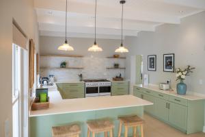 a kitchen with green cabinets and a counter with stools at Hoof House in Riebeek-Kasteel