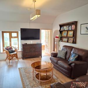 a living room with a leather couch and a tv at Cherrymount Cottage in Newcastle