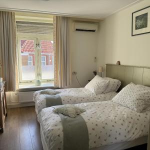 a bedroom with two beds and a window at Inn de Vijf Sinnen in Geertruidenberg
