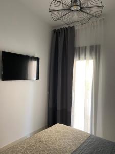 a bedroom with a bed and a television and a window at Irini Apartment in Hanioti