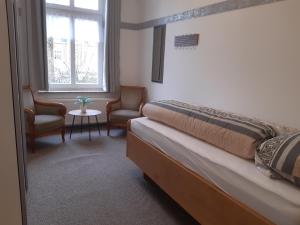 a bedroom with a bed and two chairs and a window at Meeresleuchten 1 in Emden