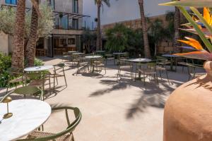 a patio with tables and chairs and palm trees at Hotel Boutique Petit París in Port de Pollensa
