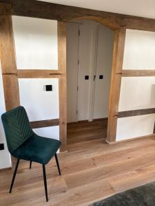 a green chair in a room with wooden floors at D'r Preëksjtool in Eygelshoven