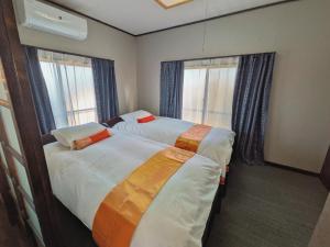 two beds in a room with two windows at 忍 Shinobi House in Yokohama