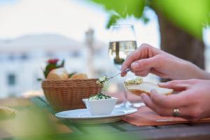 a person eating a sandwich on a table with a glass of wine at Hotel Eisbach in Ransbach-Baumbach