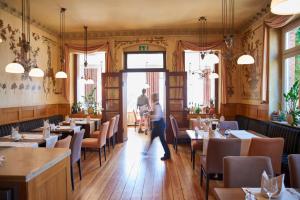 a person walking through a restaurant with tables and chairs at Hotel Eisbach in Ransbach-Baumbach