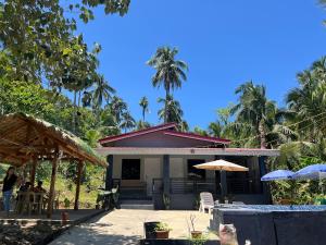 a house with a table and chairs and palm trees at Private Villa in Masbate