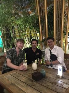 a group of three men sitting at a wooden table at Happy Bear Hostel Phu Quoc in Phú Quốc