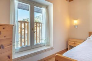 a bedroom with a bed and a window with a balcony at Leonardo al Maso Fovo in Andalo