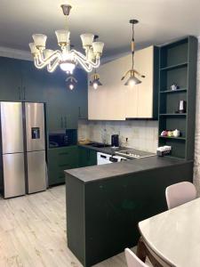 a kitchen with green cabinets and a stainless steel refrigerator at Nadia Guesthouse in Mestia