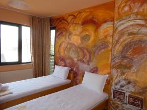 a room with two beds and a painting on the wall at Guest House Daskalov in Chervena Lokva +275 photos