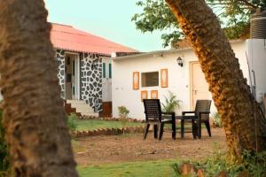 two chairs and a table in front of a house at The Coastal Nest in Daman