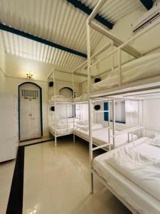 a room with three bunk beds and a hallway at The Coastal Nest in Daman