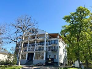 a white building with a car parked in front of it at Green Hotel Tskaltubo in Tsqaltubo
