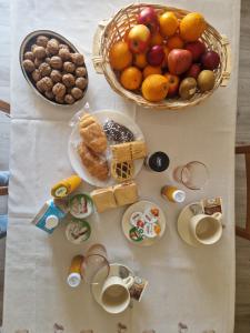 a table with a basket of fruit and plates of food at Ca d'la Mondina Apartment in Vercelli
