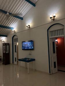 a room with a table and a tv on the wall at The Coastal Nest in Daman