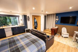 a bedroom with a bed and a couch and a television at The Hive at Bee Happy Breaks Scotland in Perth