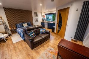 a living room with a leather couch and a bed at The Hive at Bee Happy Breaks Scotland in Perth +17 photos