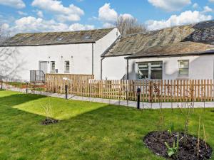 a white house with a wooden fence in a yard at 3 Bed in Crieff oc-90794 in Comrie