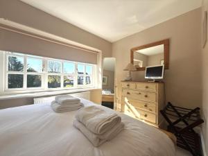 a bedroom with a white bed with a dresser and a window at Seagull Cottage, Aldwick in Bognor Regis