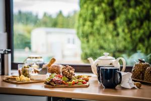 a table with two plates of food and a tea kettle at The Hive at Bee Happy Breaks Scotland in Perth