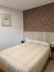 ein Schlafzimmer mit einem Bett und einer Ziegelwand in der Unterkunft Trisquel 2 in Laroá