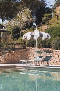 a pool with an umbrella and two lounge chairs next to it at Tuscan Relais Il Serraglio in Montepulciano