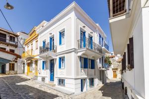 a row of white buildings with blue windows at The Blue Door - Skopelos in Skopelos Town