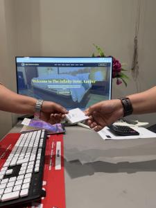 two people holding a piece of paper in front of a computer at The Infinity Hotel in Kānpur