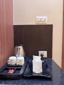 a table with two black trays with cups on it at The Infinity Hotel in Kānpur