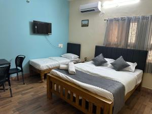 a bedroom with two beds and a table and a television at Raaha Residency in Mysore