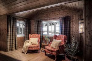 a room with two chairs and a table and windows at TH622- Premium ski-in,out Chalet with 8 bedroom, jacuzzi, sauna in Hovi