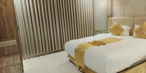 a bedroom with a large white bed with gold accents at Golden New Muhayil-نيلولوفر فور in Ḑirs