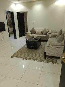a living room with two couches and a coffee table at Golden New Muhayil-نيلولوفر فور in Ḑirs