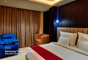 a bedroom with a bed and a blue chair at THE GRAND SUNCITY HOTEL AND RESORT, Bhopal in Bhopal